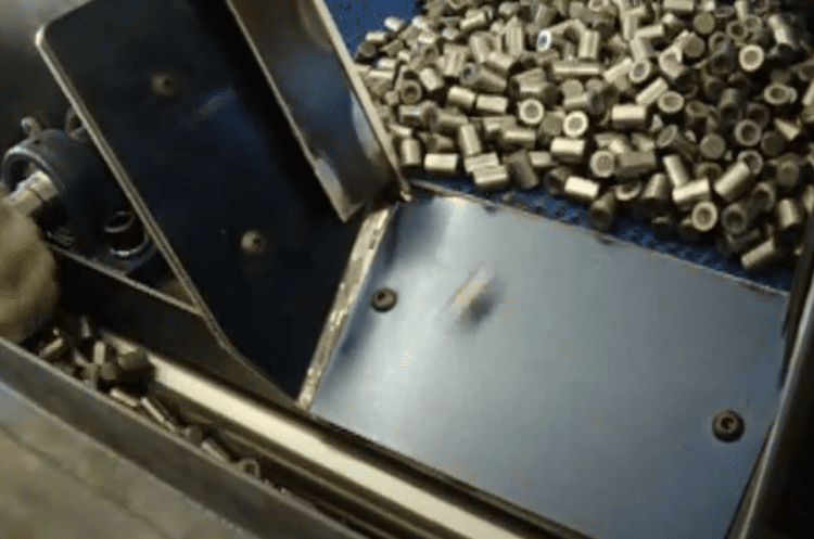 Metal casings being sorted on an industrial conveyor belt.